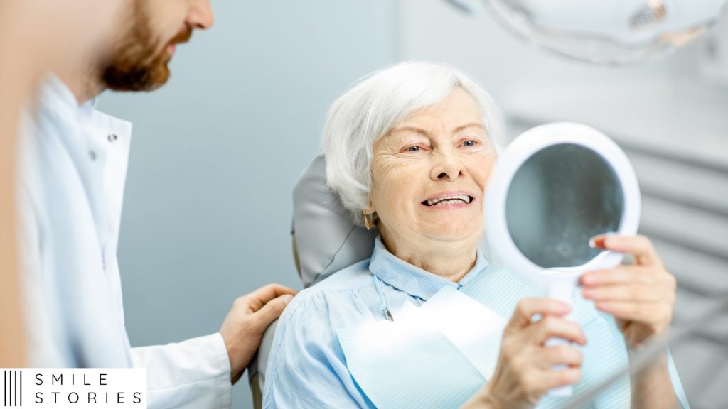 elderly lady with gray hair in a dental chair looking at her new denture implants