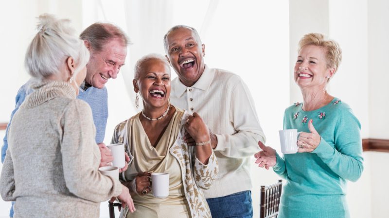 a group of five middle age people huddled together socialising