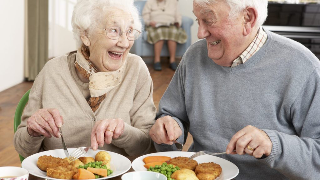 elderly couple enjoying a Sunday roast - they have dental implants