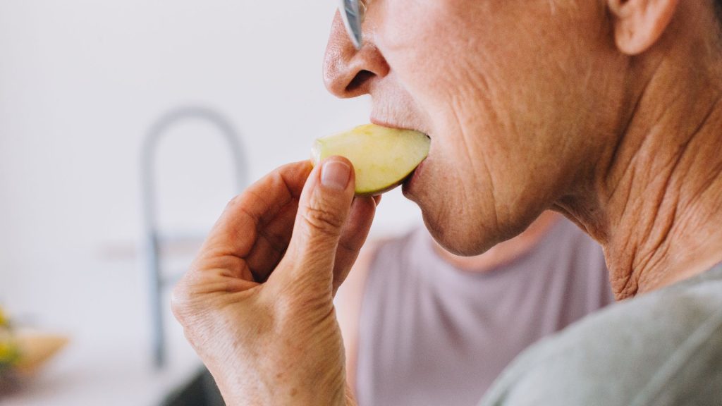 senior eating a slice of apple