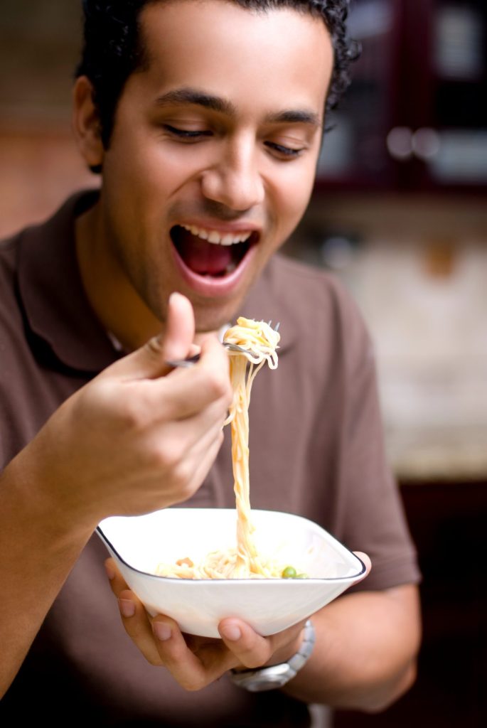 young man enjoying food - he has a single dental implants