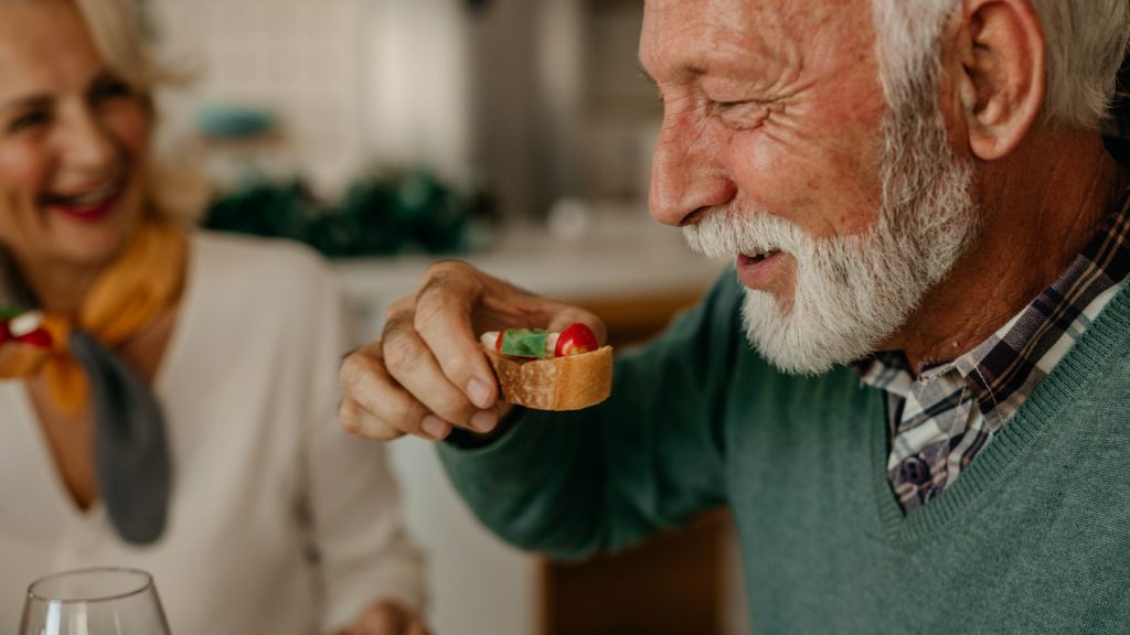 senior man with implants eating in salisbury