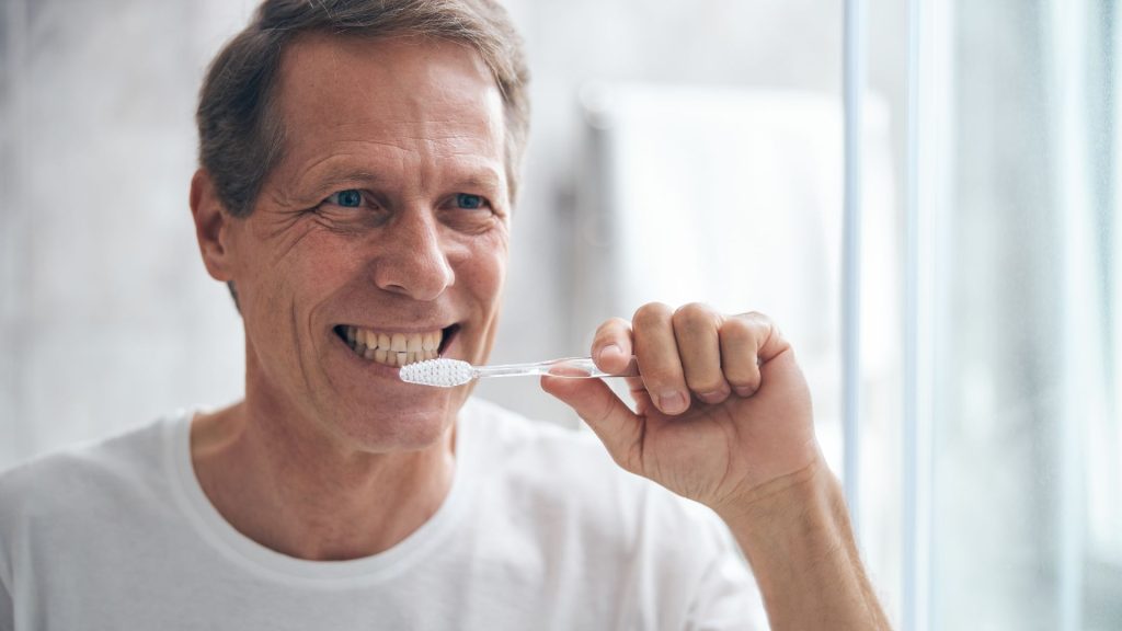 middle aged man cleaning his teeth - oral health tips